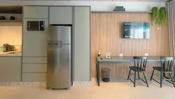 A modern kitchen with a built-in refrigerator, a microwave, and a wooden panel wall with a digital display.