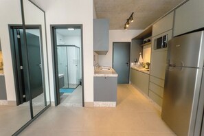 A modern kitchen with stainless steel appliances, a grey countertop, and a glass door leading to a bathroom. - Great Central Apartment for 4 Guests - CA904 (Maringá)
