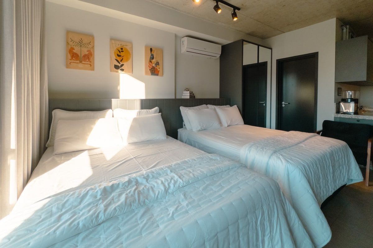 Hotellihuone, jossa on kaksi sänkyä, työpöytä ja vaatekaappi.