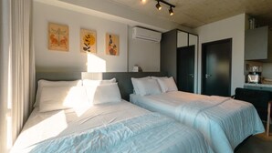 Quarto de hotel com duas camas, uma escrivaninha e um guarda-roupa.