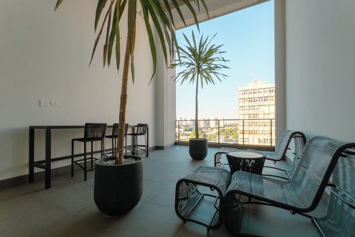 Un balcón con una zona de estar, una planta en maceta y vistas a un edificio.