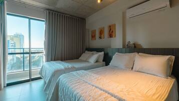 Ein Hotelzimmer mit zwei Betten, einem großen Fenster und Blick auf die Stadt.