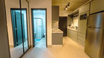 Cozinha moderna com eletrodomésticos de aço inoxidável, uma ilha central e vista para o banheiro adjacente.