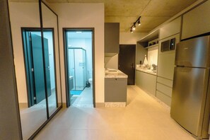 Une cuisine moderne dotée d’appareils électroménagers en acier inoxydable, d’un îlot central et donnant sur la salle de bain adjacente.