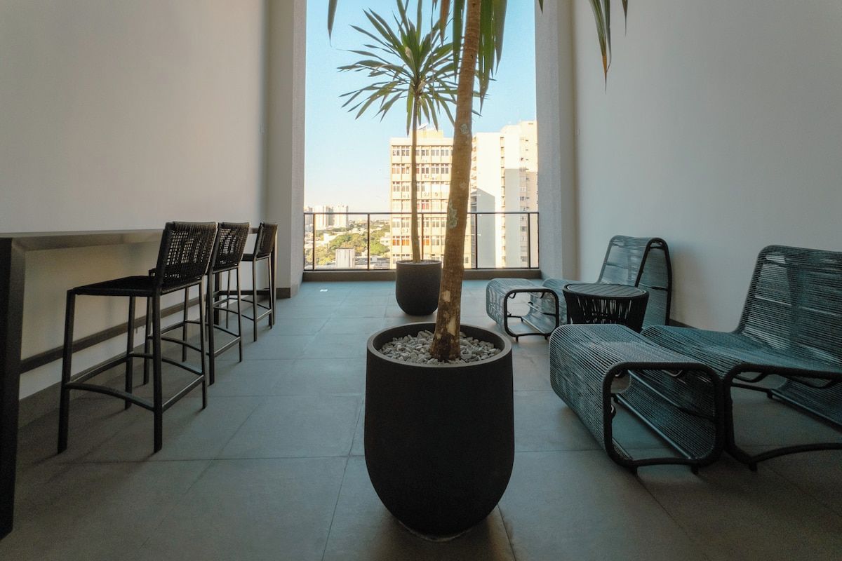 A balcony with a potted palm tree, a sofa, and two chairs.