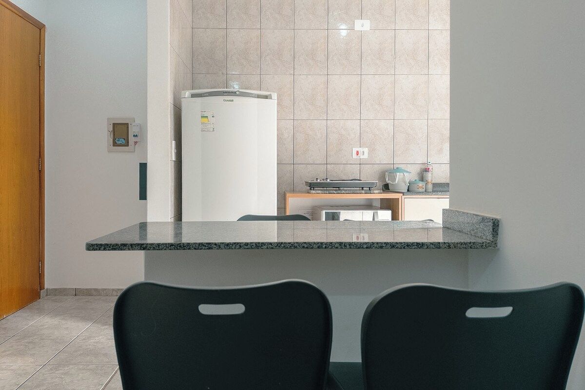 Una cocina con refrigerador, microondas y cafetera sobre la encimera.