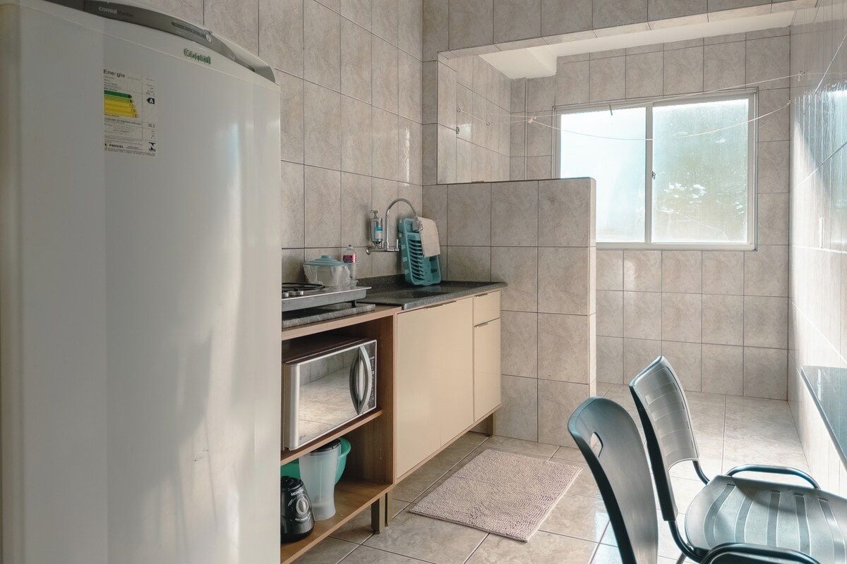 A compact kitchen with a refrigerator, a sink, and a window.