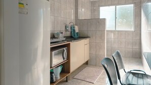 A compact kitchen with a refrigerator, a sink, and a window. - Affordable Apartment with AC in Zona 7 - CED103 (Maringá)