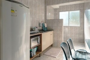 Eine kleine Küche mit Kühlschrank, Spüle und Fenster.