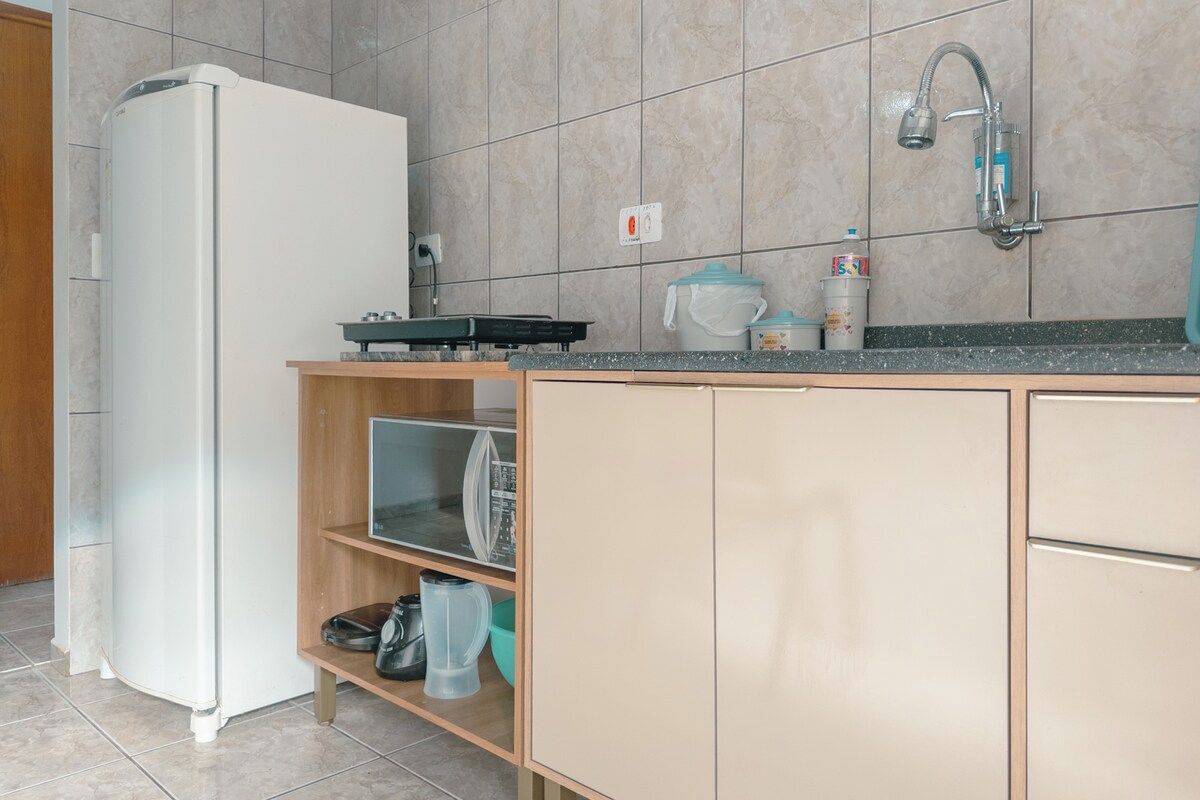 Eine Küche mit einem Kühlschrank, einem Spülbecken und einer Arbeitsplatte mit verschiedenen Gegenständen.