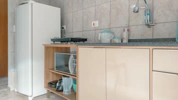 Eine Küche mit einem Kühlschrank, einem Spülbecken und einer Arbeitsplatte mit verschiedenen Gegenständen.