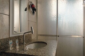 Ein Badezimmer mit Granitplatte, Waschbecken, Spiegel und Handtuchhalter.