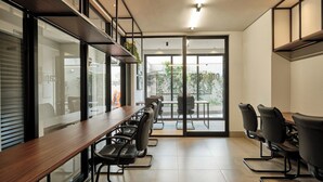 Una sala de conferencias moderna con una larga mesa y sillas, ventanas amplias y vistas al exterior.