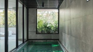 Una piscina interior moderna con techo de diseño enrejado y amplios ventanales.