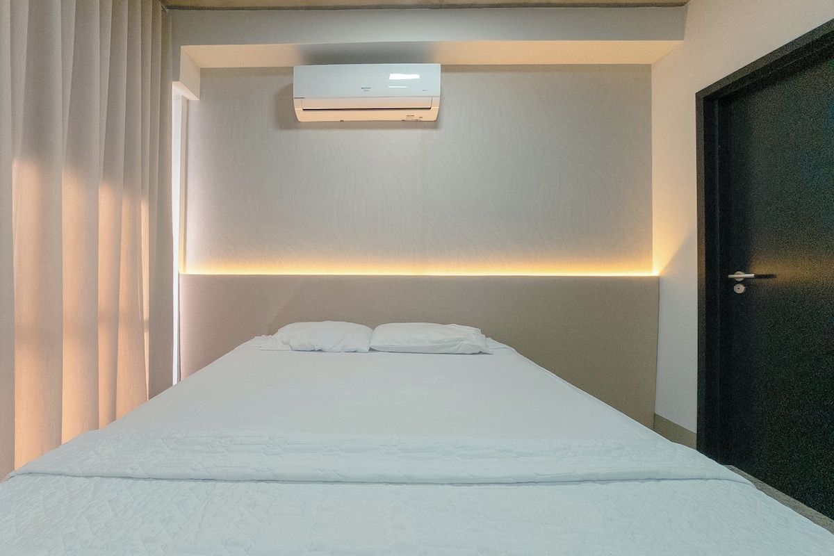 A bedroom with a bed, an air conditioning unit, a door, and a window with curtains.