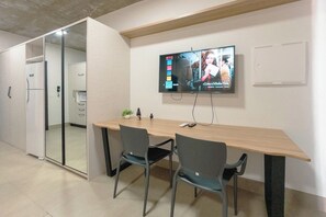 A conference room with a long table, two chairs, a TV mounted on the wall, and a glass partition.