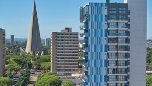 Un edificio moderno de gran altura con un diseño geométrico único, rodeado de otros edificios y zonas verdes.