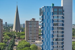 Un edificio moderno de gran altura con un diseño geométrico único, rodeado de otros edificios y zonas verdes.