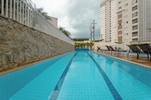 Ein Schwimmbecken mit einer Steinmauer an einer Seite und einem Gebäude im Hintergrund.