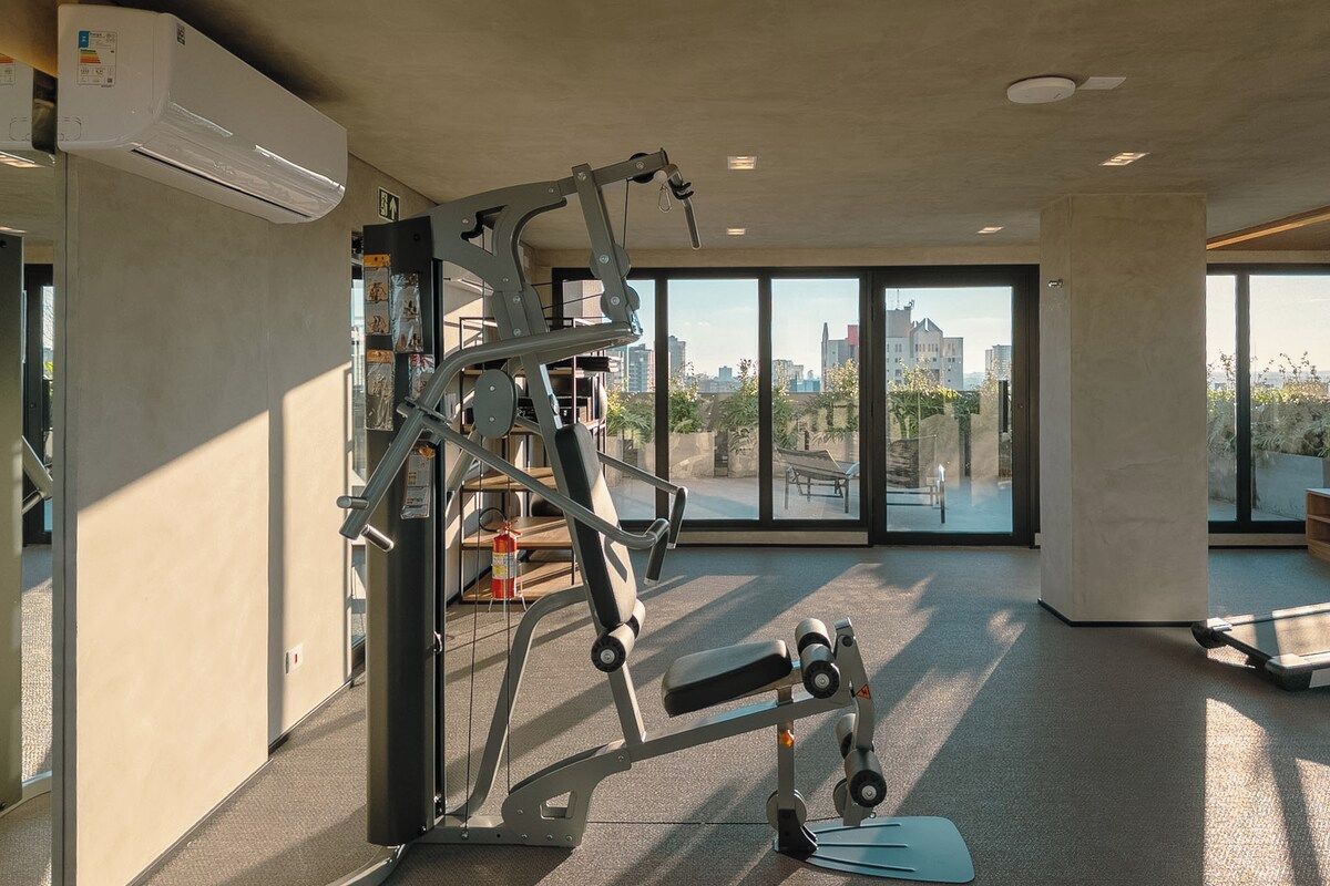A gym with exercise equipment, large windows, and a city view.