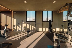A gym with exercise equipment, large windows, and a view of the cityscape.