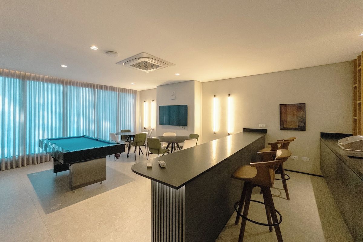 Quarto de hotel moderno com mesa de bilhar, bar e área de estar.