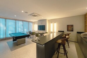 A modern hotel room with a pool table, bar area, and seating.