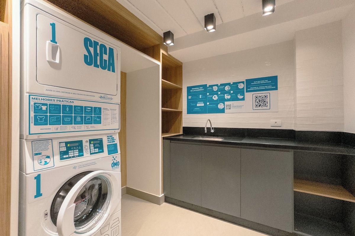 Uma lavanderia moderna com máquina de lavar, pia e cartazes informativos.
