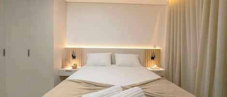 A hotel room with a large bed, bedside tables, a wardrobe, and a curtain.