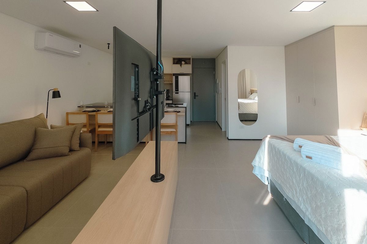 Ein modernes Hotelzimmer mit einer Couch, einem Bett, einem Schreibtisch und einer Küchenzeile.