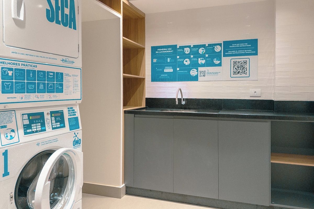 Ein moderner Waschbereich mit einer Waschmaschine, einem Waschbecken und Informationspostern an der Wand.