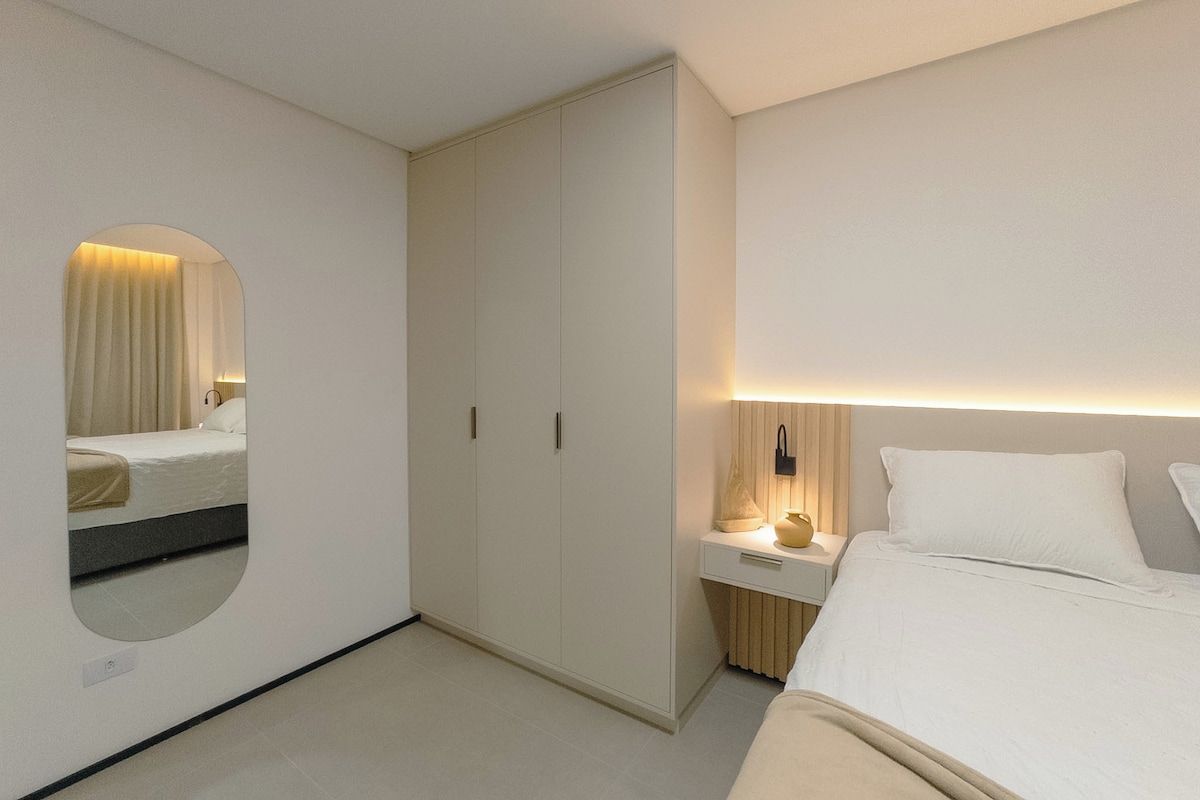 A bedroom with a bed, bedside table, lamp, and wardrobe.