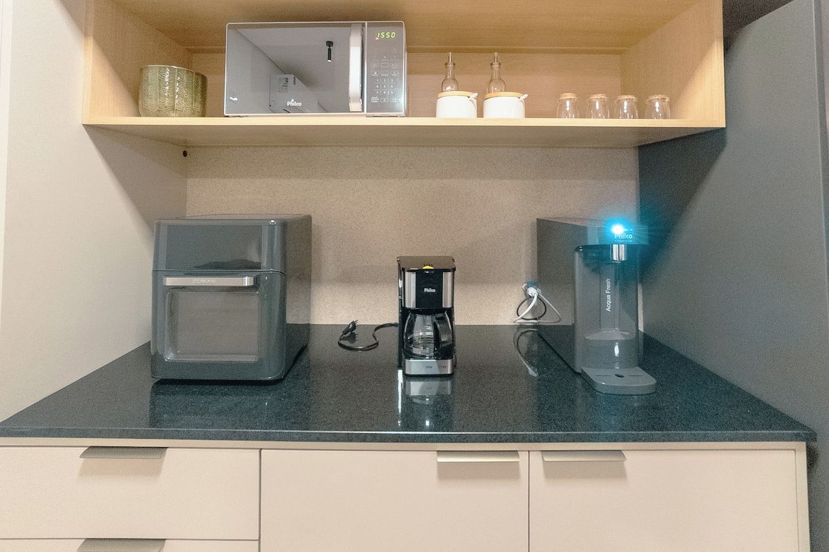 Eine Küchenzeile mit Kaffeemaschine, Wasserspender und einem Glasbehälter auf einer Arbeitsfläche.
