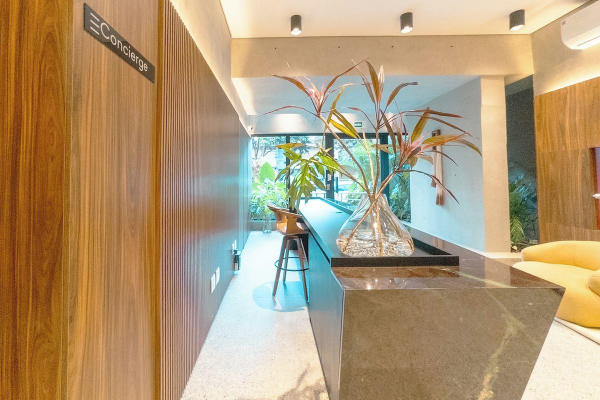 Un interior moderno con un panel de madera, una zona de bar con taburetes y una planta grande en maceta.
