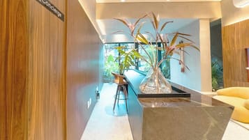 Un interior moderno con un panel de madera, una zona de bar con taburetes y una planta grande en maceta.
