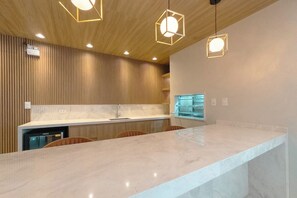 Una cocina moderna con encimera de mármol, paneles de madera e iluminación colgante.