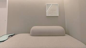 A minimalist room with a bed, a wall-mounted light fixture, and a door.