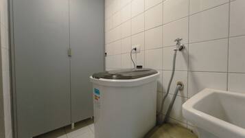 Un baño con inodoro, lavamanos y un cubo de basura.