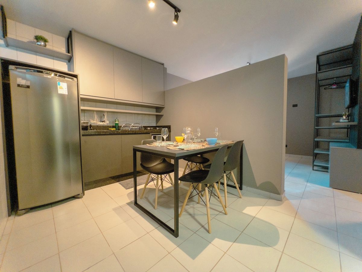A modern kitchen with a stainless steel refrigerator, a dining table with chairs, and a built-in oven.