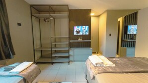 A hotel room with two beds, a wardrobe, a TV, and a small seating area. - Modern Apartment near UEM with Wi-Fi - LP12 (Maringá)