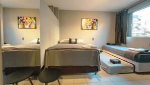 A hotel room with two beds, a sofa bed, a small table, and artwork on the walls. - Modern Apartment near UEM with Wi-Fi - LP12 (Maringá)