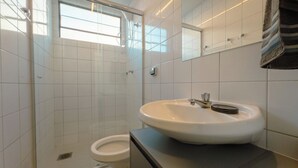 A modern bathroom with a glass shower enclosure, a white sink, and a toilet. - Modern Apartment near UEM with Wi-Fi - LP12 (Maringá)