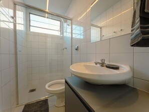 Ein modernes Badezimmer mit Duschkabine aus Glas, einem weißen Waschbecken und einer Toilette.