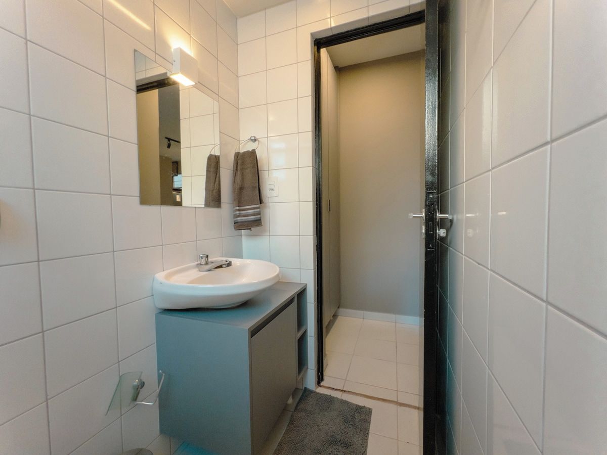 A modern bathroom with a white sink, mirror, and towel rack.