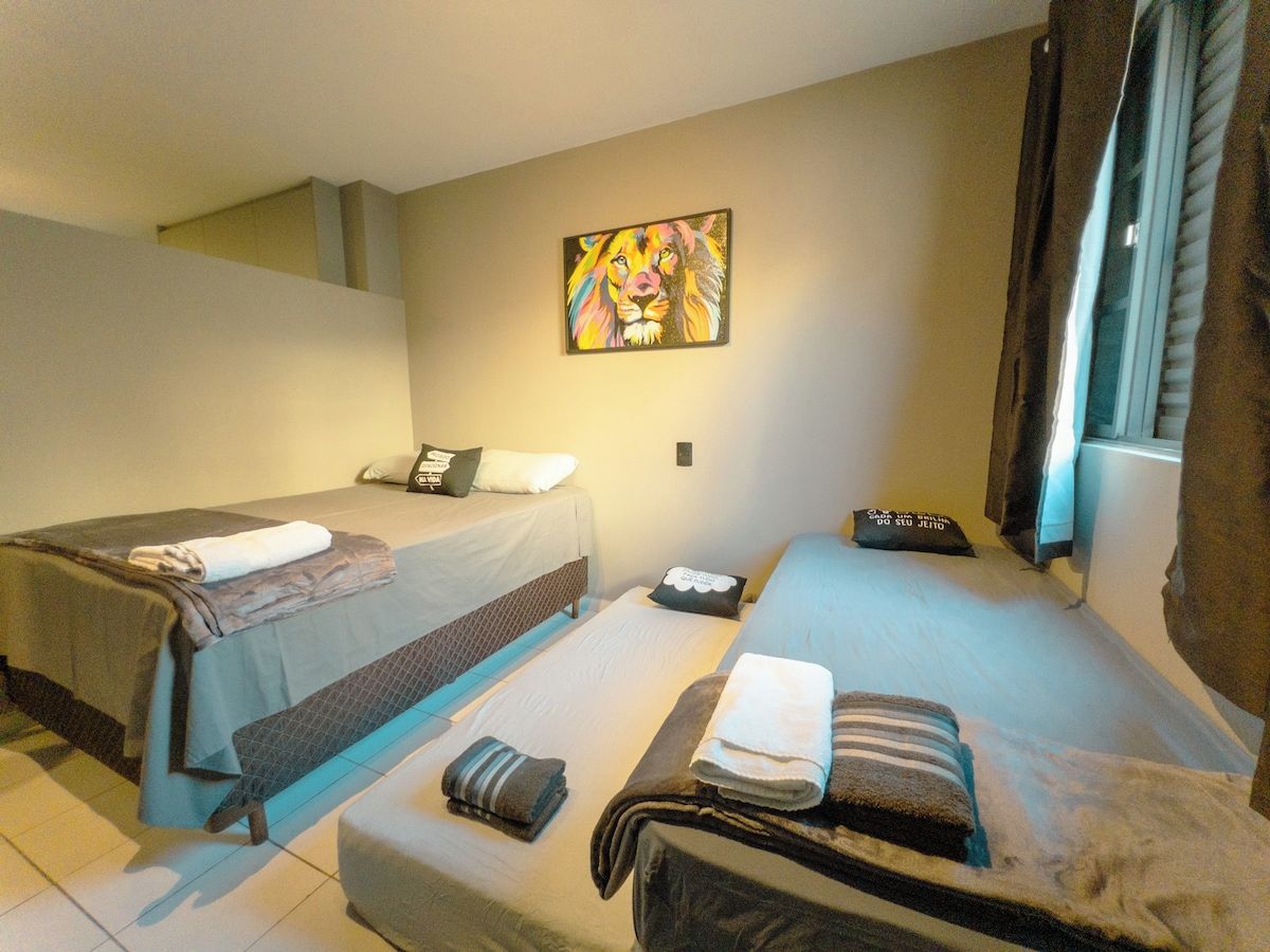 Ein Hotelzimmer mit zwei Betten, einem Bild an der Wand und einem Fenster mit Vorhängen.