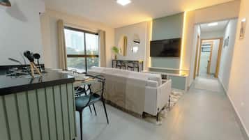 A modern living room with a sofa, a dining table, and a TV.