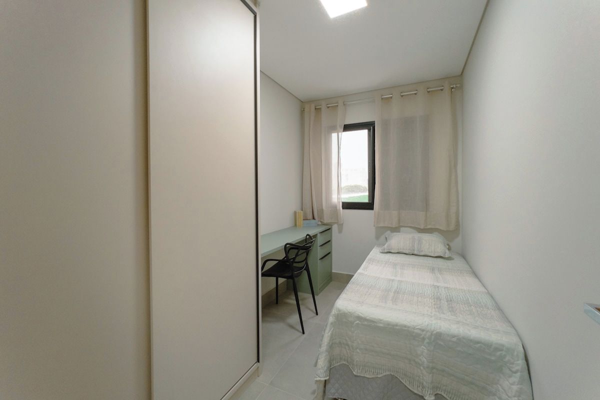 A bedroom with a bed, a desk, and a chair.