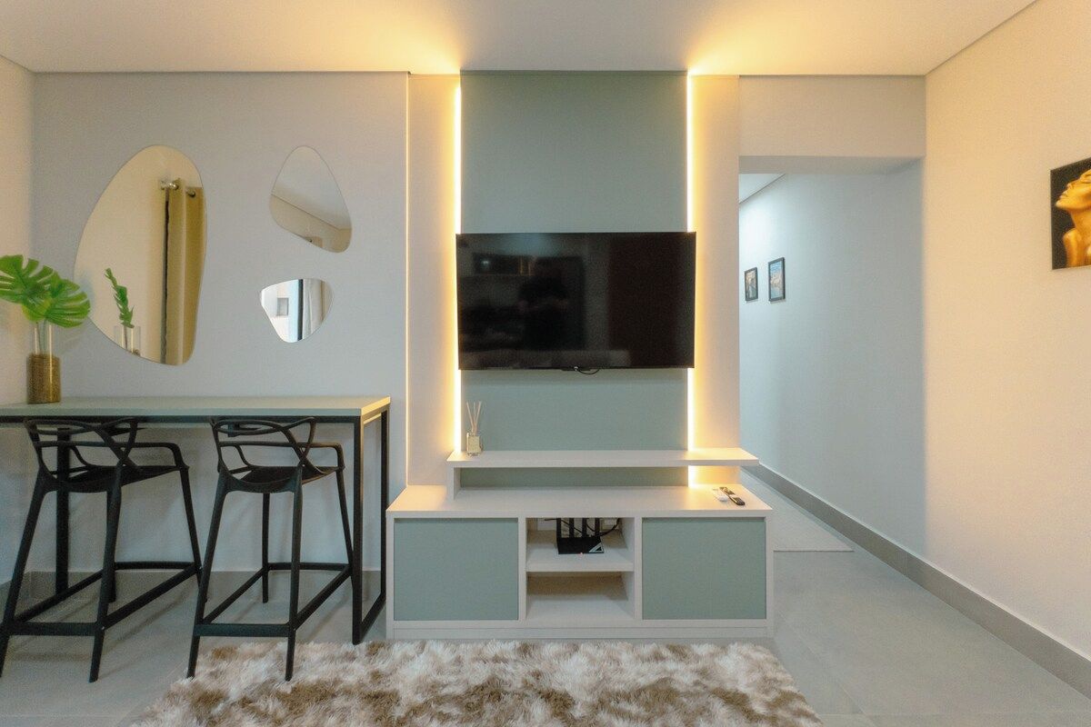 Una sala de estar moderna con un televisor de pantalla plana, un comedor con taburetes de bar y una alfombra de piel.