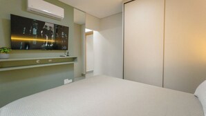 Ett hotellrum med en säng, en platt-TV som är monterad på väggen och en garderob.
