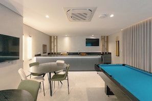 A modern room with a pool table, a dining area, and a kitchen. - Design and Modern Living in Downtown Maringa - NEO204 (Maringá)